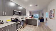 Located at 680 Hamilton Ave SE in Atlanta's Grant Park neighborhood, this single-floor residence combines contemporary design with functional living. The open-concept layout seamlessly connects the kitchen, dining, and living areas, creating a cohesive and airy atmosphere throughout.

The kitchen is outfitted with dark wood-grain cabinetry extending to the ceiling, stainless steel appliances including a range, microwave, dishwasher, and refrigerator, and granite-look countertops. The peninsula provides additional prep space and serves as a natural divider between the kitchen and living area.

Light wood-style flooring runs through the main living spaces, enhancing the sense of openness. The living room features a sliding glass door that opens to a private balcony, allowing natural light to flow in and providing outdoor views. Bold, colorful artwork adorns the walls, adding vibrancy to the neutral palette.

The bedroom is a calm retreat with plush carpeting, a ceiling fan, large windows with views to the exterior, and ample wall space accented by decorative artwork. The bathroom features granite-look countertops, dark cabinetry consistent with the kitchen, and direct access to a walk-in closet with built-in hanging storage. The entry foyer provides a clean transition into the home with light flooring and a welcoming layout.