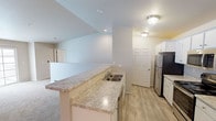 Located at 2295 Mayek Dr in Waupaca, Wisconsin, this two-floor residence offers a clean, functional layout with neutral finishes throughout. The main living level features an open-concept design where the kitchen flows directly into the living area. The kitchen is well-appointed with white cabinetry, light granite-style countertops, a peninsula with a double sink, and stainless steel appliances including a refrigerator, range, and microwave. Light wood-look flooring runs through the kitchen, complementing the bright, neutral palette. The adjacent living area is carpeted and features a sliding glass door that invites natural light, along with a ceiling fan and a wall-mounted air conditioning unit.

The upper level includes carpeted bedrooms served by natural light from windows with blinds, and baseboard heating throughout. Two bathrooms serve the residence — one with a tub/shower combo and one with a walk-in shower — both featuring light wood-look flooring, white vanity cabinetry, granite-style countertops, and wall-mounted storage cabinets. An attached garage with a concrete floor and automatic opener provides convenient enclosed parking and additional storage space.