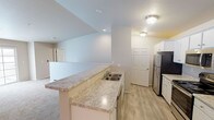 Located at 2295 Mayek Dr in Waupaca, Wisconsin, this two-floor residence offers a clean, functional layout with neutral finishes throughout. The main living level features an open-concept design where the kitchen flows directly into the living area. The kitchen is well-appointed with white cabinetry, light granite-style countertops, a peninsula with a double sink, and stainless steel appliances including a refrigerator, range, and microwave. Light wood-look flooring runs through the kitchen, complementing the bright, neutral palette. The adjacent living area is carpeted and features a sliding glass door that invites natural light, along with a ceiling fan and a wall-mounted air conditioning unit.

The upper level includes carpeted bedrooms served by natural light from windows with blinds, and baseboard heating throughout. Two bathrooms serve the residence — one with a tub/shower combo and one with a walk-in shower — both featuring light wood-look flooring, white vanity cabinetry, granite-style countertops, and wall-mounted storage cabinets. An attached garage with a concrete floor and automatic opener provides convenient enclosed parking and additional storage space.