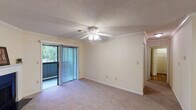 Located at Strange Court in Spartanburg, South Carolina, this single-floor unit offers a practical and comfortable layout designed for everyday living. The living area is finished with plush carpeting, crown molding, and a ceiling fan with integrated lighting, creating a bright and inviting atmosphere. A sliding glass door opens to a private balcony, framing lush greenery and providing an easy indoor-outdoor connection. The adjacent bedroom mirrors this comfortable design, featuring the same crown molding, ceiling fan, and carpeted flooring, along with a window fitted with blinds that allows natural light to fill the room. The kitchen is equipped with warm wood cabinetry, ample upper and lower storage, a double-basin sink, a dishwasher, a refrigerator, and a range, all set over durable hardwood-style flooring. Crown molding continues throughout, lending a cohesive, finished look to the space. The bathroom is well-appointed with an extended vanity countertop, dual sinks, a large wall mirror, and hardwood-style flooring, complemented by a shower-tub combination. A textured ceiling is a consistent detail throughout the unit. Overall, the space presents a straightforward, functional design with thoughtful finishing touches throughout.