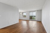 Located on the 8th floor at 350 Elliott St in Windsor, Ontario, this 2-bedroom, 1-bathroom unit offers a practical and well-appointed layout across a single floor. Warm-toned hardwood-style flooring flows consistently throughout the living areas and bedrooms, lending a cohesive and inviting feel to the space.

The living room is the heart of the unit, featuring a large sliding glass door that opens to a private balcony with outdoor views, allowing for generous natural light. A pendant light fixture adds a simple decorative touch, while baseboard heating ensures year-round comfort. The open feel of the living area provides versatile space for both relaxing and entertaining.

The primary bedroom is a well-sized room with its own window overlooking the surrounding neighbourhood, a baseboard heater, and a full-width double closet with sliding doors — offering ample storage. The second bedroom also features a window with natural light, hardwood-style flooring, vertical blinds, and a baseboard heater.

The bathroom is finished with classic white subway tile surrounding a full soaker tub and shower combination, fitted with polished chrome fixtures for a clean and timeless look.

A hallway connects the rooms efficiently, and the unit's neutral white walls and textured ceilings throughout provide a clean, move-in-ready canvas.