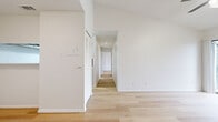This well-designed 2-bedroom, 2-bathroom single-floor residence offers a clean, minimalist aesthetic throughout. Light hardwood flooring flows consistently across every room, complementing the crisp white walls and creating a bright, cohesive atmosphere.

The kitchen is thoughtfully appointed with white shaker-style cabinetry, white quartz countertops, a subway tile backsplash, a stainless steel double sink, a dishwasher, and a refrigerator. A hallway with a louvered closet door connects the main living area to the rest of the unit.

Both bedrooms feature ceiling fans with integrated lighting, large windows that invite natural light and outdoor views, and light hardwood flooring. The primary bedroom is generously sized and includes access to a dedicated walk-in closet outfitted with built-in shelving and hanging rods, providing ample storage.

Each of the two bathrooms is finished consistently, featuring a tub-shower combination with white tile surround, light hardwood flooring, a white vanity with quartz countertop, and brushed nickel hardware and fixtures.

The entry area opens cleanly into the main living space, with a flush-mount ceiling light and a louvered storage closet nearby. Overall, the space presents a fresh, move-in-ready environment with a neutral palette and modern finishes throughout.