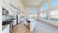 Located at 1480 E Paseo Verde Pkwy in Henderson, NV, this well-appointed 2-bedroom, 3-bathroom residence offers a thoughtfully designed single-level layout with impressive architectural details throughout. The heart of the home is a dramatic open-concept living, dining, and kitchen area distinguished by soaring double-height ceilings and an expansive wall of floor-to-ceiling windows that floods the space with abundant natural light and provides views of the surrounding area. A private balcony extends the living space outdoors. The kitchen is equipped with stainless steel appliances, including a refrigerator, gas range, microwave, and dishwasher, complemented by white cabinetry, a tile backsplash, dark countertops, and a central island with a sink. Light wood-style flooring runs throughout the main living areas, while plush carpet adds warmth to the bedrooms. Each bedroom features walk-in closets with wire shelving systems. The primary bathroom includes a dual-sink vanity with dark countertops and white cabinetry. Three full bathrooms provide ample convenience. Additional highlights include a dedicated laundry area, a utility room, and a welcoming entrance hallway, making this a complete and functional residence.