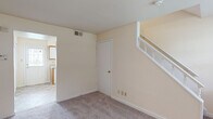 Located at 6701 Dartmouth Avenue in Richmond, VA, this two-story home offers a practical and well-organized layout across two floors. The main level features a carpeted living room with a white-railed staircase leading to the upper floor, a closet, and a kitchen equipped with wood-trimmed cabinetry, white appliances including a range, dishwasher, and refrigerator, complemented by tile flooring and a back door providing exterior access. Natural light filters through multiple windows fitted with blinds throughout the home. The full bathroom on the upper level includes a tiled tub-shower combination, a vanity with storage, tile flooring, and a window for natural ventilation. Three bedrooms are spread across both floors, each featuring soft carpet, neutral cream-toned walls, and windows that bring in outdoor views of the surrounding neighborhood. The spacious primary bedroom offers a generous footprint among the three rooms. A hallway connects the upper-level spaces efficiently. The home's consistent warm neutral palette, carpeted living areas, and tile in wet areas create a clean, cohesive interior throughout.