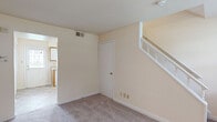 Located at 6701 Dartmouth Avenue in Richmond, VA, this two-story home offers a practical and well-organized layout across two floors. The main level features a carpeted living room with a white-railed staircase leading to the upper floor, a closet, and a kitchen equipped with wood-trimmed cabinetry, white appliances including a range, dishwasher, and refrigerator, complemented by tile flooring and a back door providing exterior access. Natural light filters through multiple windows fitted with blinds throughout the home. The full bathroom on the upper level includes a tiled tub-shower combination, a vanity with storage, tile flooring, and a window for natural ventilation. Three bedrooms are spread across both floors, each featuring soft carpet, neutral cream-toned walls, and windows that bring in outdoor views of the surrounding neighborhood. The spacious primary bedroom offers a generous footprint among the three rooms. A hallway connects the upper-level spaces efficiently. The home's consistent warm neutral palette, carpeted living areas, and tile in wet areas create a clean, cohesive interior throughout.