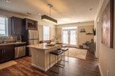 Located at 525 Kempsville Rd in Virginia Beach, Virginia, this single-floor residence offers a thoughtfully designed layout with a seamless flow between living spaces. The living room makes a welcoming first impression, featuring warm hardwood-style flooring, neutral walls, and a set of French doors with transom windows that invite an abundance of natural light and provide outdoor access. The kitchen is a standout feature, outfitted with rich dark cabinetry, granite countertops, stainless steel appliances including a range, microwave, dishwasher, and refrigerator, and a peninsula with bar seating — ideal for casual dining or entertaining. Hardwood-style flooring continues throughout the main living and kitchen areas. The residence includes multiple bedrooms, each carpeted for comfort, with generous closet space and large windows that allow natural light to fill the rooms. Two full bathrooms serve the home — one featuring a tub-shower combination with white tile surround, and the other offering a sliding glass-door walk-in shower, both with hardwood-style flooring. A dedicated in-unit laundry area accommodates a full-size washer and dryer with overhead shelving. The overall aesthetic is warm and neutral, creating a comfortable, move-in-ready environment.