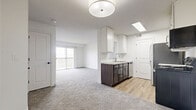 This single-floor, 3-bedroom, 1-bathroom unit offers a functional and well-appointed layout designed to maximize everyday livability. The open-concept kitchen and living area form the heart of the home, where light-toned carpet flows through the living space and transitions to wood-look luxury vinyl plank flooring in the kitchen. The kitchen is equipped with stainless steel appliances — including a range, microwave, and refrigerator — complemented by two-tone cabinetry featuring white upper cabinets and dark lower cabinets, as well as light granite-style countertops and a stainless steel sink. A textured ceiling and flush-mount lighting illuminate the space throughout. The living area is bright and airy, benefiting from a sliding glass door that opens to a private balcony with exterior views. Each of the three bedrooms features plush carpeting, white walls, and ample natural light from sliding or standard windows. The primary bedroom offers a comfortable footprint suited for a full bedroom suite. The full bathroom includes a shower-tub combo, a dark-cabinetry vanity with a white countertop, and wood-look flooring, maintaining a consistent design aesthetic. A connecting hallway ties all rooms together efficiently, creating a cohesive and practical floor plan.