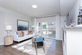 Located at 12883 S Brundisi Way in Herriman, Utah, this single-floor 2-bedroom, 2-bathroom residence offers a thoughtfully designed layout with modern finishes throughout. The open-concept living and kitchen area serves as the heart of the home, where a granite-topped island with bar seating connects seamlessly to the living space. The kitchen features white cabinetry, stainless steel appliances, and granite countertops. The living room is bathed in natural light from a sliding glass door that opens to a private balcony, and includes a built-in fireplace flanked by shelving. Wood-look flooring flows throughout the main living areas, adding warmth and continuity. The primary bedroom is a comfortable retreat with plush carpet, generous natural light from a large window, and direct access to a well-appointed closet. Both bathrooms feature white vanities with granite countertops and wood-look flooring; one includes a tub-shower combo with tile surround. A dedicated laundry area with in-unit washer and dryer adds everyday convenience. Neutral tones and clean lines throughout create a bright, inviting ambiance well-suited to modern living.