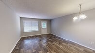 Located at 8050 Taylor Rd in Riverdale, GA, this single-story, 3-bedroom, 2-bathroom home offers a practical and well-organized layout across one level. The living area greets you with rich wood-look flooring, neutral gray walls, a textured ceiling, and natural light streaming through blinded windows flanking a paneled entry door — creating a bright and welcoming atmosphere. An elegant pendant chandelier illuminates a connected dining area, which opens to the kitchen via a pass-through window. The kitchen features white cabinetry with modern bar-pull hardware, light speckled countertops, a stainless steel dishwasher, and wood-look flooring, offering a clean and functional workspace. Two connecting hallways guide you to the private quarters of the home. The bedrooms are finished with soft, neutral carpet and offer adequate space for furnishings, with ceiling vents ensuring comfortable climate control. The primary bedroom provides a comfortable retreat with a dedicated closet. Both bathrooms are identically appointed with a single-sink vanity featuring speckled countertops, a full tub-shower combination with white tile surround, and wood-look flooring — presenting a consistent, tidy aesthetic throughout the home.