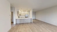Located at 15922 E Valleyway Ave in Spokane, Washington, this well-appointed unit offers a clean, modern aesthetic with a thoughtfully designed single-floor layout. The open-concept living and kitchen area serves as the heart of the space, featuring light hardwood-style flooring that extends throughout the main areas. The kitchen is outfitted with light wood cabinetry, a full suite of stainless steel appliances including a refrigerator, electric range, and microwave, and a large peninsula with a quartz countertop and undermount sink. Stylish pendant lights hang above the peninsula, adding a contemporary touch. The living area is bright and open, with a glass-panel door providing access to a private balcony and outdoor views. The bedrooms are carpeted for comfort, each with windows that allow natural light and views of the surrounding neighborhood. A well-designed bathroom includes a wood-toned vanity with a quartz countertop, a framed mirror, and a full tub-shower combination, all set on light hardwood-style flooring. Throughout the unit, neutral tones and recessed lighting create a clean, cohesive ambiance suited for modern living.