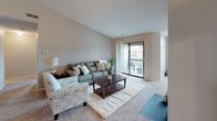 Located at 5147 Lancaster Hills Dr in Clarkston, Michigan, this single-floor residence offers a well-organized layout designed for comfortable everyday living. The living room is bright and welcoming, featuring plush carpeting, neutral tones, and a large sliding glass door that opens to a private balcony, providing an abundance of natural light and outdoor access. Adjacent to the living room, the dining area is defined by vaulted-style walls and a chandelier overhead, creating an intimate setting ideal for gatherings. The galley-style kitchen is efficiently designed with light wood cabinetry, ample counter space, wood-look flooring, and includes essential appliances such as a refrigerator, electric range, and dishwasher. The primary bedroom features large windows with outdoor views, soft carpeting, and direct access to a walk-in closet. A second bedroom is equally well-lit, benefiting from dual windows that frame views of the surrounding greenery. Two full bathrooms serve the residence, each featuring wood-look flooring, a vanity with storage, and a shower-tub combination. Additional closet space is found throughout, enhancing the overall storage capacity of the home. The neutral color palette and consistent finishes give the space a cohesive and move-in ready feel.