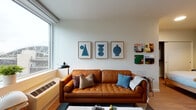 Located in the heart of Portland's vibrant West End neighborhood, this single-floor residence at 1725 SW Salmon St offers a well-appointed and modern living experience. The open layout is anchored by a bright living area featuring large windows that frame urban views of the surrounding cityscape, flooding the space with natural light. Light wood flooring runs throughout, lending warmth and continuity to each area.

The kitchen is efficiently designed with dark wood cabinetry, stainless steel appliances including a gas range, a crisp white countertop, and a distinctive hexagonal tile backsplash that adds a contemporary geometric touch. Recessed lighting and a well-organized layout make it a functional and visually appealing space.

The bedroom offers a calm, restful retreat with a deep green accent wall, a sliding-door closet with built-in organization, and a sleek wall-mounted reading lamp. The bathroom is finished with clean white subway tile in the shower and a charming dark accent wall with a gold dot pattern, adding a playful yet sophisticated touch.

Throughout the residence, the design balances modern minimalism with warm, curated details, creating an inviting atmosphere that is both practical and stylish — ideal for comfortable urban living in Portland.