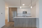 Located at 155 Greenbrier Rd in Cambridge, Ontario, this thoughtfully designed one-bedroom, one-bathroom unit offers a clean, contemporary aesthetic throughout its efficiently laid-out single floor. The open-concept kitchen and living area serves as the heart of the unit, featuring a sleek island with a white quartz countertop, an undermount sink, and warm wood-toned cabinetry that extends to the ceiling. Stainless steel appliances, including a French door refrigerator, built-in microwave, and range, add a polished, modern touch, while pendant lighting above the island creates an inviting ambiance. Light hardwood-style flooring flows seamlessly through the living spaces, complementing the crisp white walls and lending warmth to the interior. The bedroom is a calm, well-proportioned retreat featuring a large window that frames outdoor views and floods the room with natural light. The bathroom is finished with large-format neutral tile surrounds a deep soaker tub with a combined shower, complemented by modern chrome fixtures. Throughout the unit, the design balances functionality with contemporary style, creating a bright, cohesive living environment well-suited for comfortable everyday living.