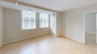 Located at 733 15th St NW in the heart of Washington, DC, this modern single-floor unit offers a clean, contemporary design throughout. The open-concept layout connects the living and dining areas seamlessly to the kitchen, creating a bright and functional living space. Light hardwood flooring runs throughout the main living areas, lending warmth and cohesion to the interior.

The kitchen is a standout feature, equipped with sleek dark cabinetry, a bold black granite countertop island with an integrated sink, stainless steel appliances including a refrigerator, microwave, and range, and track lighting overhead that highlights the space effectively.

The living areas are generously proportioned, with multiple large windows dressed with horizontal blinds that allow ample natural light while offering city views of the surrounding Washington, DC urban landscape. The neutral, warm-toned walls complement the light flooring throughout.

The bathroom is well-appointed with large-format tile flooring, a soaking tub with full tile surround, a mirrored vanity, and dark cabinetry with a white countertop. Notably, an in-unit stacked washer and dryer is conveniently located adjacent to the bathroom, adding significant practical value to this centrally located DC residence.