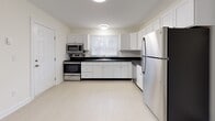 Located at 77 Newfield Ave in Waterbury, Connecticut, this single-floor residence offers a clean, well-maintained layout designed for comfortable everyday living. The spacious living room is dressed in neutral gray tones with crown molding, plush carpeting, and a large sliding glass door fitted with vertical blinds that opens to a private balcony, filling the room with natural light and outdoor views. Adjacent to the living area, the kitchen is outfitted with white cabinetry, dark countertops, light vinyl flooring, and a full suite of stainless steel appliances including a range, microwave, dishwasher, and refrigerator. A window above the sink adds natural light to the workspace. The residence features two carpeted bedrooms, each with windows dressed in horizontal blinds and baseboard heating. One bedroom offers double closets, providing generous storage space. Two bathrooms serve the home: a full bath with a tub-shower combination, single vanity, and light vinyl flooring, and a second bathroom featuring a framed mirror, a stylish gray vanity with ample drawer storage, and updated fixtures. Throughout the home, white trim and a soft, neutral color palette create a cohesive and inviting atmosphere.