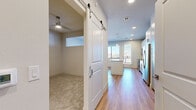 This single-floor unit offers a thoughtfully designed layout that maximizes its compact footprint. The kitchen serves as a central highlight, featuring stainless steel appliances including a range, microwave, and refrigerator with ice maker. White shaker-style cabinetry with brushed gold and silver hardware pairs with granite countertops, while a subway tile backsplash adds a clean, modern touch. A central island with pendant lighting above provides additional workspace and casual seating. Large windows allow abundant natural light and offer exterior views, enhancing the open feel of the kitchen and living area.

Light hardwood flooring flows throughout the main living spaces, transitioning to plush carpet in the additional room, which features a ceiling fan and a clerestory window. A distinctive sliding barn door separates this room from the main hallway, adding a stylish architectural detail.

The two bathrooms maintain consistent finishes, including granite-topped vanities with gray cabinetry and wood-tone flooring. One bathroom includes a tiled shower-tub combination with brushed nickel fixtures, while the other functions as a half bath. Recessed lighting and large mirrors contribute to a bright, clean ambiance throughout both bathrooms. The overall design is modern, cohesive, and efficiently arranged.