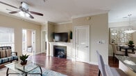 This single-floor residence offers a thoughtfully designed open-concept layout that seamlessly connects the kitchen, dining, and living areas. The kitchen is outfitted with rich, dark espresso cabinetry extending to the ceiling, dark granite countertops, black appliances including a refrigerator, electric range, and built-in microwave, and a multi-seat breakfast bar with pendant lighting overhead. Crown molding throughout adds a polished architectural detail.

The living room is bright and inviting, featuring warm hardwood-style flooring, a ceiling fan, and large windows with horizontal blinds that allow generous natural light. A fireplace with a classic white mantle serves as a focal point, and a sliding glass door leads to a private balcony with views of the surrounding area. An adjacent dining area accommodates a full-sized table beneath a pendant light fixture.

The bedrooms are carpeted and comfortably sized, each equipped with a ceiling fan and windows that bring in natural light. The bathroom features dark cabinetry, granite countertops, a dark-framed mirror, and a tub-shower combination. The entryway transitions smoothly from the front door into the kitchen and main living spaces, creating a cohesive and functional flow throughout the home.