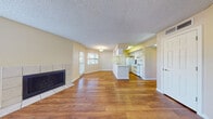 This single-floor residence offers a well-organized layout with a bright, open-concept living and dining area at its core. The living room is a welcoming space, featuring warm wood-look flooring, multiple windows that invite natural light, and a classic tile-surround fireplace that serves as a focal point. A flush-mount light fixture and textured ceiling complete the room's clean, functional aesthetic.

The kitchen is efficiently designed with a wraparound peninsula that opens to the living area, white cabinetry, light countertops, a double-basin sink, and a full suite of white appliances including a refrigerator, electric range, and built-in microwave. A tall pantry cabinet provides additional storage, and the wood-look flooring continues seamlessly throughout.

The bedrooms are carpeted and finished with warm neutral tones, each equipped with ceiling fans and windows fitted with blinds for natural light and privacy. The rooms offer comfortable, versatile spaces suitable for a variety of configurations.

The bathroom is neatly appointed with a wide vanity featuring white cabinetry and a large mirror, a tiled shower-tub combination, and wood-look flooring that ties the space together. Throughout the residence, consistent finishes — including textured ceilings, white trim, and soft yellow-toned walls — create a cohesive and practical living environment.