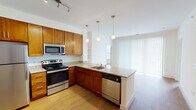 This single-floor residence offers a thoughtfully designed layout that balances functionality and comfort throughout its living spaces. The kitchen serves as a standout feature, showcasing warm honey-toned cabinetry, light granite countertops, and a full suite of stainless steel appliances including a refrigerator, range, microwave, and dishwasher. Elegant pendant lighting illuminates the peninsula, which also houses a stainless steel sink, while a built-in open shelving unit adds a practical yet decorative touch. Natural light filters in through large windows fitted with vertical blinds, connecting the kitchen to the adjacent living area. The bedrooms are finished with plush neutral carpet and light-toned walls, creating a calm and restful atmosphere. Each room benefits from natural light through horizontal-slatted blinds, and one bedroom features a closet with built-in shelving for added storage. The two bathrooms maintain a clean, cohesive aesthetic with tile flooring, granite-topped vanities with warm wood cabinetry, and white tilework in the shower area. Throughout the home, white trim, neutral wall tones, and consistent finishes contribute to a bright, well-maintained, and move-in-ready environment.