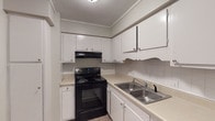 This single-floor 2-bedroom home offers a clean, functional layout with a neutral color palette and modern finishes throughout. The kitchen is equipped with white upper and lower cabinetry, a tile backsplash, light countertops, a double-basin stainless steel sink, and a black electric range with overhead ventilation — providing ample storage and workspace for everyday cooking. The living area features warm-toned vinyl plank flooring and a set of French doors that flood the space with natural light while offering direct access to the outdoors. Both bedrooms are well-proportioned, each featuring the same durable vinyl plank flooring, neutral wall tones, textured ceilings, and windows that bring in generous natural light with views of the surrounding greenery. The bathroom includes a full tub-shower combo with white tile surround and chrome fixtures, while a separate water closet with grab bar provides additional convenience and accessibility. Throughout the home, crisp white trim and consistent finishes create a cohesive and move-in-ready atmosphere suited for comfortable everyday living.
