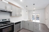 This contemporary apartment spans three floors, offering a blend of style and functionality. The heart of the home is a well-appointed kitchen, showcasing light gray cabinetry, quartz countertops, and stainless steel appliances. The L-shaped layout maximizes space efficiency, while pendant lights add a touch of elegance.

The living areas boast wood-look flooring, creating a warm and inviting atmosphere. Large windows flood the rooms with natural light, offering urban views and a sense of openness. The bathroom continues the modern aesthetic with a clean white palette, featuring a vanity with ample storage and a shower/tub combination.

Each floor is thoughtfully designed, with the upper levels likely housing bedrooms and additional living spaces. The apartment's open concept design promotes a seamless flow between areas, ideal for both everyday living and entertaining. Recessed lighting throughout ensures a bright, welcoming environment at any time of day.

The property's attention to detail is evident in its neutral color scheme, allowing residents to easily personalize their space. With its combination of style, comfort, and urban sophistication, this three-floor apartment offers a desirable living experience in a contemporary setting.