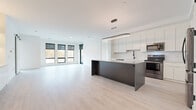 Located on Parkview Road in Brecksville, Ohio, this contemporary single-floor residence showcases a clean, modern design with an emphasis on open living and high-quality finishes throughout. The heart of the home is a spacious open-concept kitchen and living area, unified by light-toned hardwood flooring and a crisp white palette. The kitchen is thoughtfully appointed with tall white cabinetry, white quartz countertops, a full subway tile backsplash, a matte black spring-neck faucet with an undermount sink, and a suite of stainless steel appliances. A sleek dark-toned island anchors the space, complemented by a modern oval pendant light overhead. The living area benefits from an abundance of natural light through large black-framed windows that frame views of the surrounding autumn foliage. A sliding barn door adds an architectural accent to one of the flexible living spaces, which also features built-in shelving with integrated lighting. Bedrooms are generously sized, with floor-to-ceiling windows and access to an outdoor balcony in one room. A spacious walk-in closet provides extensive built-in shelving and hanging storage. The bathrooms feature marble-look tile flooring, white floating vanities with quartz countertops, undermount sinks, matte black fixtures, and backlit LED mirrors, delivering a refined, spa-like atmosphere throughout.