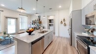 Located at 2381 West Main Street in Midlothian, TX, this well-designed one-bedroom, one-bathroom unit offers a thoughtful layout across a single floor. The kitchen serves as a central highlight, featuring grey shaker-style cabinetry, granite countertops, a large island with an undermount sink and dishwasher, and a full suite of stainless steel appliances including a refrigerator, range, and microwave. Light wood-style flooring and pendant lighting above the island contribute to a modern, airy aesthetic. In-unit laundry connections are visible just off the kitchen area. The bedroom is carpeted and generously sized, bathed in natural light from multiple windows with blinds and curtain panels. A ceiling fan adds comfort, and the room offers ample space for a full furniture arrangement. The walk-in closet provides built-in shelving and rod storage, maximizing organization. The bathroom is finished with the same grey cabinetry and granite countertops found in the kitchen, and includes a tiled tub-shower combination with wood-look flooring. Throughout the unit, the clean white walls and consistent finishes create a cohesive, contemporary feel suitable for comfortable everyday living.
