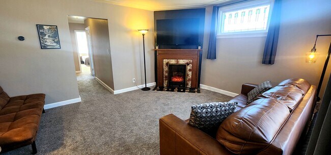 Luminosa sala de estar con gran ventanal, acogedora chimenea y TV montada en la pared. - 822 E 4th St