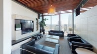Located in the heart of downtown Charlotte at 350 W 5th St, this single-floor space delivers a striking contemporary design with an emphasis on luxury finishes and sweeping city views. Floor-to-ceiling glass windows frame breathtaking panoramic vistas of the Charlotte skyline, flooding the interiors with abundant natural light throughout the day.

The open-plan kitchen is a standout feature, showcasing an expansive island with a light stone countertop, dark cabinetry with under-cabinet accent lighting, a textured stone backsplash, stainless steel double wall ovens, and a bold industrial-style island range hood. A second kitchen or entertaining bar area features a polished marble island, sleek bar stools, and dramatic reflective dark tile flooring that mirrors the cityscape beyond the glass.

The living and lounge areas are elegantly appointed with black leather seating, a wood-slatted ceiling detail, a built-in media wall, and a warm area rug anchoring the space. Curated modern artwork and sculptural pendant lighting add artistic character throughout. A dedicated lounge area with a tufted white accent wall, contemporary art, and minimalist white and black furniture provides an intimate retreat. The overall ambiance is polished, urban, and refined, ideal for high-end entertaining or professional use.