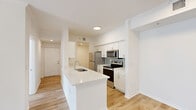 Located in Miramar, FL, this well-appointed 2-bedroom, 1-bathroom single-story home offers a clean, modern aesthetic throughout. Light wood-tone flooring flows seamlessly across every room, creating a warm and cohesive feel. The open-plan living area is bright and airy, highlighted by a ceiling fan and easy access to the kitchen.

The kitchen is a standout feature, equipped with white shaker cabinetry, a light quartz countertop island with an undermount sink, light blue subway tile backsplash, and a full suite of stainless steel appliances including a refrigerator, microwave, and electric range. The layout connects effortlessly to the main living space.

The primary bedroom is generously sized, featuring a ceiling fan, a closet, and direct access to an additional hallway or storage area. The second bedroom offers natural light through large windows with blinds and its own ceiling fan. A third room with sliding glass doors opens to an outdoor view, filling the space with abundant natural light.

The bathroom is finished in a bright white palette, with a shaker-style vanity, quartz countertop, a tub/shower combination with tiled surround, and a natural light window. Three hallways provide functional circulation throughout the home, which also includes a dedicated closet for additional storage.