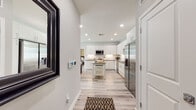 This well-designed single-floor residence offers a thoughtful layout with modern finishes and a cohesive neutral color palette throughout. The entry hall, with light wood-look flooring and a smart thermostat panel, opens directly into the kitchen — a standout feature of the home. The kitchen is outfitted with floor-to-ceiling white cabinetry, dark quartz countertops, a subway tile backsplash with under-cabinet lighting, and a full suite of stainless steel appliances including a French door refrigerator, range, microwave, and dishwasher. A freestanding island with a lower storage shelf adds versatility to the space.

The living room is bright and airy, with large windows on multiple walls that invite abundant natural light and views of the outdoors. Light wood-look flooring continues throughout the main living areas, lending a clean, contemporary feel.

The bedrooms offer plush carpeting, ceiling fans, and windows with blinds that allow for natural light and privacy. The primary bathroom features a large vanity with dark countertops and white cabinetry, while the secondary bathroom includes a full soaking tub and tiled surround. Both bathrooms are finished with matching light wood-look flooring, creating a consistent and polished aesthetic throughout the residence.