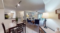 Located at 2664 N McMullen Booth Rd in Clearwater, Florida, this single-floor residence offers a well-designed layout with a warm coastal aesthetic throughout. The open-concept living and dining area features tile flooring, carpet, a ceiling fan, and track lighting, creating a bright and comfortable atmosphere. Large sliding glass doors in the living room flood the space with natural light and open to a private patio overlooking lush greenery. The kitchen is equipped with white cabinetry, dark granite countertops, stainless steel appliances including a range, microwave, and refrigerator, along with a double sink — offering both style and functionality. Two well-appointed bedrooms each feature plush carpet, ceiling fans, and windows with sheer curtains that allow ample natural light. The primary bedroom includes a spacious closet. Both bathrooms are finished with dark granite vanity counters, white cabinetry, and tile flooring. The primary bathroom features a tub-shower combination, while the second bathroom offers a tub-shower setup as well. The overall ambiance of the space is bright, clean, and inviting, with a consistent coastal-inspired design theme carried throughout.