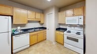 Located at 100 Kimball Ave in Salem, Virginia, this single-floor unit offers a straightforward, functional layout across several well-defined spaces. The floor plan, visible in the 3D model, reveals a practical arrangement of living, sleeping, kitchen, and bathroom areas connected by a logical flow.

The kitchen is well-equipped, featuring light wood cabinetry with ample upper and lower storage, dark countertops, and tile flooring. White appliances include a refrigerator, electric range with overhead microwave, and dishwasher, providing a complete cooking setup. A stainless steel sink is positioned along the countertop with additional prep space nearby.

The living area is carpeted and generously sized, highlighted by a large sliding glass door fitted with vertical blinds that allow natural light to filter in and provide outdoor access. The bedrooms are also carpeted and feature neutral wall tones, with windows fitted with horizontal blinds offering natural light. Ceiling fans with integrated lighting are present in multiple rooms, enhancing comfort and airflow.

The bathroom includes a full tub and shower combination with white tile surround, complemented by tile flooring that transitions into the carpeted hallway beyond. Overall, the space presents a clean, functional environment suited for everyday living.