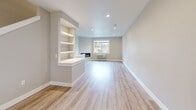 This three-story home in Keizer, Oregon, offers a well-organized layout spread across three distinct levels, combining modern finishes with functional design throughout. The ground floor houses an attached garage featuring a contemporary paneled door with frosted glass panels, a clean concrete floor, and an electrical panel — providing practical utility from the moment you enter.

The main living level serves as the heart of the home, centering around an open-concept kitchen and living area. The kitchen stands out with crisp white shaker cabinetry, a striking quartz waterfall island, stainless steel appliances, pendant lighting, and a window overlooking the outdoors. The adjacent living room features light hardwood-style flooring, recessed lighting, a built-in electric fireplace with integrated shelving, and a sliding glass door that connects seamlessly to a private fenced patio and yard.

The upper floors accommodate four bedrooms, including a generously sized primary suite, serviced by three full bathrooms. The bathrooms feature clean white surrounds, soaking tubs, wood-look flooring, and matte black hardware accents. Bedrooms are bright, with large windows framing neighborhood views. Two closets, including a well-equipped walk-in, provide ample storage. Neutral warm-gray walls and light flooring carry a cohesive, contemporary palette throughout.