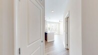Located at 5220 Center St in Williamsburg, VA, this thoughtfully designed one-bedroom, one-bathroom residence offers an efficient and comfortable single-floor layout. The open-concept kitchen and living area serves as the heart of the home, featuring rich dark-wood cabinetry, stainless steel appliances, and a granite-topped peninsula illuminated by elegant pendant lighting. Light hardwood-style flooring runs throughout the main living areas, complementing the neutral color palette and creating a bright, cohesive atmosphere. A ceiling fan and large windows with access to an outdoor balcony flood the living space with natural light and views of the surrounding area. The bedroom offers plush carpeting, soft neutral tones, and access to a dedicated closet, providing a calm and comfortable retreat. The bathroom continues the refined aesthetic with dark wood cabinetry, a granite vanity countertop, and hardwood-style flooring. A dedicated laundry area adds everyday convenience. Throughout the residence, clean architectural lines, recessed lighting, and quality finishes come together to create a polished and inviting living environment.