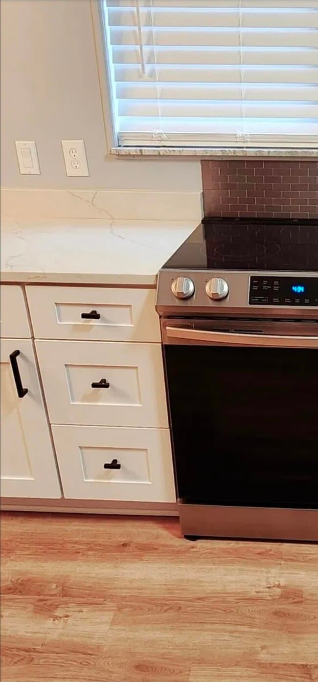 La vista de cerca de la cocina resalta los gabinetes detallados, los herrajes modernos y la elegante gama de acero inoxidable. - 21 Richmond Sq