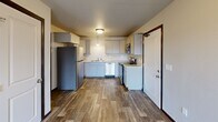 Located at 3411 Jaffa Garden Way in Rapid City, South Dakota, this 2-bedroom, 2-bathroom single-floor home offers a practical and comfortable layout. The kitchen is a standout feature, showcasing gray shaker-style cabinetry, light countertops, a stainless steel appliance suite including a refrigerator, electric range, built-in microwave, and dishwasher, along with wood-look plank flooring and pendant lighting that adds a modern touch. Both bathrooms are finished with the same wood-look flooring, white cabinetry with ample counter space, and full tub/shower combinations with clean white surrounds. The bedrooms are carpeted and bathed in natural light from windows fitted with blinds. The spacious primary bedroom comfortably accommodates a full bedroom suite. The second bedroom mirrors the same warm, neutral tones and carpeted comfort. A dedicated closet provides additional storage, while the in-unit laundry area includes a washer and dryer alongside a water heater, adding everyday convenience. Throughout the home, dark-trimmed doorframes provide a clean contrast to the neutral walls, creating a cohesive and modern aesthetic.