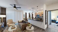 This thoughtfully designed 1-bedroom, 1-bathroom residence offers a smart and efficient single-floor layout that maximizes every square foot. The open-concept living and kitchen area serves as the heart of the home, where wood-toned cabinetry, dark quartz countertops, a tiled backsplash, and a full suite of stainless steel appliances — including a gas range, over-the-range microwave, and refrigerator — come together in a sleek, functional kitchen. Elegant globe pendant lights hang above the peninsula, which doubles as a dining or prep space. The living area features wood-look flooring, a ceiling fan, and large windows dressed with layered curtains that invite natural light while maintaining privacy. The bedroom is a comfortable retreat highlighted by a bold accent wall, plush carpeting, a ceiling fan, and a spacious open closet with built-in shelving and hanging rods. The full bathroom includes a tub-shower combination with clean white tile surround. A dedicated laundry room with a side-by-side washer and dryer and overhead wire shelving adds exceptional convenience. Throughout, the space presents a modern, cohesive aesthetic with crisp white walls and warm wood accents.