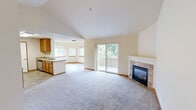 Located at 6801 S 133rd St in Seattle, WA, this single-floor, 3-bedroom, 2-bathroom home offers a well-designed layout with thoughtful architectural details throughout. The open living room is a standout, featuring soaring vaulted ceilings, plush carpeting, and a corner stone-tile fireplace that serves as a natural focal point. Sliding glass doors lead to a private balcony overlooking mature greenery, filling the space with abundant natural light. The kitchen is efficiently designed with warm honey-toned cabinetry, light countertops, stainless steel appliances including a range, microwave, refrigerator, and dishwasher, and durable tile flooring. The layout connects seamlessly to the living area. The primary bedroom offers generous proportions with vaulted ceilings, soft carpet, a sliding-door closet with built-in shelving, and direct access to an en-suite bathroom. The additional bedrooms also feature vaulted ceilings and carpet, with ample closet space. Both bathrooms are finished with tile flooring, wood-toned vanities, and tub/shower combinations. A connecting hallway ties the rooms together cohesively, making this home functional and comfortable throughout.