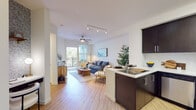 Located at 6701 Eton Ave in Canoga Park, CA, this well-appointed single-floor residence offers a thoughtfully designed open-concept layout that seamlessly integrates the kitchen, dining, and living areas. Light wood-style flooring flows throughout the main living spaces, complemented by crisp white walls and ceiling fans that enhance the airy atmosphere.

The kitchen is a standout feature, outfitted with rich dark espresso cabinetry extending to the ceiling for ample storage, stainless steel appliances including a gas range, microwave, and refrigerator, and a light-colored countertop with an undermount sink. A peninsula connects the kitchen to the living area, ideal for casual dining or entertaining.

The living room is bright and welcoming, bathed in natural light from a sliding glass door that opens to a private balcony with outdoor views. Track lighting and a ceiling fan complete this comfortable gathering space.

The bedroom is a serene retreat, featuring plush carpeting, a ceiling fan, natural light from dual windows with blinds, and a distinctive patterned accent wall. A spacious walk-in closet with built-in shelving and hanging rods provides generous storage.

The bathroom is finished with dark wood cabinetry, a wide vanity with an undermount sink, bright overhead lighting, and a large mirror, all set over matching wood-style flooring.