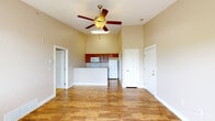 This single-floor unit offers a well-designed open-concept layout that seamlessly connects the kitchen and living areas. Vaulted ceilings throughout the main living space create a sense of openness and volume, complemented by a ceiling fan that adds both function and style. The living area features warm hardwood-style flooring, neutral beige walls, and generous natural light flowing in through large windows fitted with horizontal blinds. A sliding door provides direct access to a private balcony with outdoor views of surrounding greenery.

The kitchen is appointed with rich medium-toned wood cabinetry, granite-style countertops, a double stainless steel sink, and white appliances including an electric range with overhead microwave. A peninsula counter serves as a natural divider between the kitchen and living space, offering additional prep and seating potential.

The bathroom features a full tub-and-shower combination, a wood-vanity with a granite-topped single sink, a large mirror, and consistent hardwood-style flooring. Additional rooms accessible from the main living area include a carpeted bedroom and a closeted storage space, completing a functional and cohesive floor plan. The overall ambiance is clean, neutral, and move-in ready.