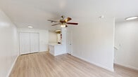 Located at 9888 United Dr in Houston, TX, this two-story unit is thoughtfully laid out across two equally sized floors, offering a practical and comfortable living arrangement. Light wood-style flooring runs throughout both levels, creating a clean, cohesive aesthetic that enhances the sense of openness.

The ground floor hosts a combined kitchen and living area. The kitchen is outfitted with white cabinetry, light stone countertops including a peninsula, a stainless steel sink, black appliances — including an electric range, dishwasher, and refrigerator — and a skylight-style overhead fixture that keeps the space well-lit. The adjacent living area benefits from a large picture window that invites natural light and outdoor views, complemented by a ceiling fan with a built-in light fixture.

The second floor features a dedicated living room with large windows framing lush outdoor scenery, along with a ceiling fan to maintain airflow. A full bathroom on this level includes a combined shower and soaking tub with white tile surround. A closet provides additional storage. A staircase connects both floors seamlessly.

Throughout the unit, the clean white walls and light flooring contribute to a bright, airy ambiance that feels welcoming and move-in ready.