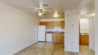 Located at Las Brisas Way in Sierra Vista, Arizona, this one-bedroom, one-bathroom unit offers a practical and functional layout across a single floor. Wood-look luxury vinyl flooring runs consistently throughout the space, lending a cohesive and clean aesthetic to every room.

The kitchen is well-appointed with warm oak-toned cabinetry that extends to the ceiling, providing generous storage. A full suite of white appliances includes a refrigerator, dishwasher, electric range with overhead ventilation, and a double-basin sink. The countertops offer ample prep space in an efficient L-shaped configuration.

The bedroom is a bright, comfortable space featuring a window that invites natural light and offers an exterior view. The room is finished with the same wood-look flooring and clean white walls, creating a simple and airy atmosphere. A dedicated closet is accessible directly from the bedroom, offering convenient built-in storage with a hanging rod.

The hallway connects the living areas and provides access to the bathroom, which includes a full-size soaking tub and shower combo with a white surround, toilet, and towel bars. The layout also accommodates a washer and dryer hookup within the closet area, adding practical everyday functionality to this efficiently designed unit.
