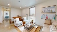 Located on Venice Boulevard in the heart of Los Angeles, this one-bedroom, one-bathroom unit offers a clean, modern aesthetic throughout its efficiently designed single-floor layout. The open-concept kitchen and living area serves as the heart of the home, featuring a sleek kitchen outfitted with white flat-front cabinetry, light quartz countertops, stainless steel appliances including a refrigerator and dishwasher, and a undermount sink. The living area flows seamlessly from the kitchen, bathed in natural light from a large window that frames views of the surrounding neighborhood. Recessed lighting and polished concrete-style flooring lend a contemporary feel to the shared space. The bedroom is a bright, comfortable retreat with two oversized windows on adjacent walls, flooding the room with natural light and offering open views of the Los Angeles skyline and streetscape. Carpeted flooring and warm, neutral tones create a calm atmosphere. A dedicated closet provides convenient storage. The bathroom features a clean, all-white tiled tub-shower combination with chrome fixtures, maintaining the unit's crisp, minimalist style. A hallway connects the rooms, and in-unit laundry adds everyday convenience. The overall ambiance is bright, airy, and modern.