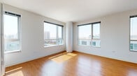 Located at 1188 Mission Street in San Francisco's SoMa neighborhood, Unit 2222 is a well-appointed single-floor residence that combines modern design with practical functionality. Throughout the unit, warm-toned hardwood flooring provides a cohesive and inviting aesthetic that flows seamlessly from room to room.

The living area is bright and open, featuring large floor-to-ceiling sliding windows on two sides that frame sweeping city views and flood the space with abundant natural light. A distinctive cylindrical architectural column adds a modern structural accent to the corner of the room.

The kitchen is designed with clean lines and ample storage, featuring white cabinetry, dark granite countertops, a stainless steel sink, and a dishwasher. A pass-through opening connects the kitchen to the adjacent living area, enhancing the open feel of the unit.

The bedrooms are generously sized, each benefiting from large windows that capture natural light and city views. One bedroom includes a spacious walk-in closet with built-in wire shelving, while another features a standard closet with organized shelving. A vertical panel radiator and thermostat are also present, ensuring climate control.

The bathroom is finished in crisp white tile flooring and walls, featuring a full bathtub with a window above, a toilet, and a built-in shelving unit for storage.