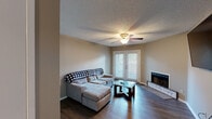 Located at 600 Firestone Ave in Muscle Shoals, Alabama, this single-floor residence offers a well-organized layout designed for comfortable everyday living. The living room serves as the heart of the home, featuring rich dark hardwood-style flooring, a ceiling fan with light fixture, a fireplace, and French doors fitted with white shutters that allow natural light to filter in. Adjacent to the living area is a charming dining nook with a custom built-in bench seat finished in white with a dark wood top, complemented by a matching solid wood table — a distinctive and practical design detail. The kitchen is laid out in a galley style, equipped with warm oak cabinetry, granite-toned countertops, and white appliances including a range and over-the-range microwave, all set atop light-toned luxury vinyl flooring. The primary bedroom is generously sized with dark hardwood-style floors, a ceiling fan, a spacious double closet, and a private en-suite bathroom featuring a granite-topped vanity. The second bedroom is well-proportioned with a window for natural light and a ceiling fan. A second full bathroom with a tub/shower combination and granite vanity completes the layout. Textured ceilings and neutral warm-toned walls are consistent throughout, giving the home a cohesive and inviting feel.