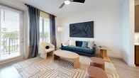 Located in Saint Petersburg, FL, this well-appointed one-bedroom, one-bathroom residence offers a thoughtfully designed open-concept layout. The combined kitchen and living area serves as the heart of the home, showcasing warm wood-toned cabinetry, stainless steel appliances, a large kitchen island with a quartz countertop and pendant lighting, and light hardwood-style flooring. The living area is bright and inviting, featuring a ceiling fan, large windows dressed with floor-to-ceiling drapes, and direct access to a private balcony with neighborhood views. The bedroom is a comfortable retreat with plush carpeting, natural light from a sizable window, and ample space for a full suite of furniture. Four closets provide generous storage throughout the unit. The bathroom is finished with large-format marble-style tile, a glass-enclosed walk-in shower, a wood-panel vanity with a white countertop, and direct access to a walk-in closet. The overall aesthetic is clean and modern, with a neutral palette accented by contemporary fixtures. This residence is well-suited for those seeking a stylish, low-maintenance living space in the heart of Saint Petersburg.