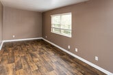 Located at 2627 Wimpole Ave in Knoxville, Tennessee, this single-floor home offers a cohesive and functional layout connected by a central hallway. The interior is defined by rich, dark wood-look flooring that runs throughout the main living areas, complemented by deep taupe and brown wall tones and clean white baseboards that provide a modern, grounded aesthetic. Ceiling fans provide overhead lighting and airflow in the main living area, while flush-mount light fixtures illuminate the hallway and bathroom.

The kitchen is well-equipped with warm oak cabinetry extending to the upper and lower walls, dark granite-style countertops, a double-basin sink, and a freestanding electric range, offering ample storage and workspace. The bathroom features a wooden vanity with a white basin sink, a wall-mounted mirror with vanity lighting, and matching dark wood-look flooring, maintaining a consistent design language throughout.

The bedrooms are bright and comfortable — one features dark wood-look flooring with a large window framing outdoor greenery, while another is finished with plush carpet and a generous window that fills the room with natural light and neighborhood views. The overall layout, as seen from the dollhouse view, is compact yet efficient, making practical use of every area throughout this Knoxville home.