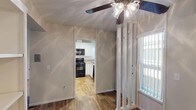 This single-story residence offers a well-organized layout with distinct living, sleeping, and kitchen areas. The living room is a standout space, featuring vaulted ceilings accented by an exposed dark wood beam and a large sliding glass door fitted with vertical blinds, allowing generous natural light and outdoor views. Carpet flooring runs throughout the living and bedroom areas, contributing to a warm, comfortable atmosphere.

The kitchen is efficiently designed with white cabinetry, granite-style countertops, wood-look flooring, and a suite of black appliances including a gas range, over-the-range microwave, and sink. A pass-through opening connects the kitchen to the adjacent living area, enhancing the sense of openness.

The bedrooms are carpeted and feature ample natural light from windows dressed with vertical blinds. One bedroom includes a mirrored closet, while another offers a walk-in closet with built-in shelving and vaulted ceilings, adding to the sense of spaciousness.

The bathroom includes a full tub-shower combination with chrome fixtures, a granite-topped vanity, and a clean, neutral finish throughout. A ceiling fan with a light fixture is installed in the main living area, completing the functional design of this well-appointed space.