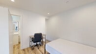 Located at 3001 Van Buren Pl in Los Angeles, CA 90008, this efficiently designed one-bedroom, one-bathroom unit offers a clean, modern aesthetic across a single floor. The bedroom is the heart of the space, featuring warm light wood laminate flooring, crisp white walls, and recessed lighting that creates a bright and airy atmosphere. A standout architectural detail is the sliding barn door, which adds a contemporary touch while maximizing the use of space. A window with decorative iron grillwork allows natural light to fill the room, and the layout comfortably accommodates a bed and a work desk, making it functional for everyday living. Entry to the unit is secured by a keypad-enabled door, providing modern convenience and privacy. The bathroom continues the clean, minimalist design language with matching light wood flooring, white walls, and a white vanity. A window above the toilet mirrors the decorative ironwork found in the bedroom, maintaining visual consistency throughout. The shower area features classic white tile, completing the bathroom's fresh and tidy appearance. Overall, this unit presents a well-maintained, thoughtfully finished space well-suited for single occupancy in the Los Angeles area.